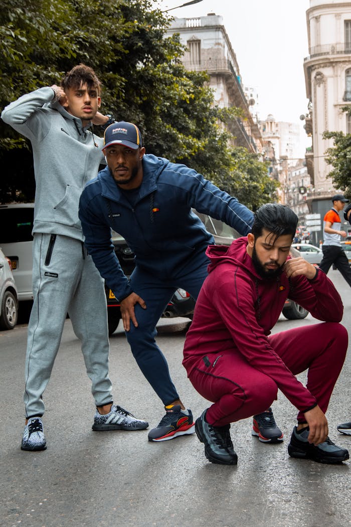 Three men pose in stylish active wear on a city street, embodying modern urban fashion.